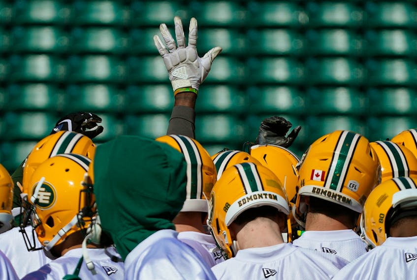A lone hand is raised during a team huddle during training camp for the Edmonton Football Club at Commonwealth Stadium on May 20, 2019.