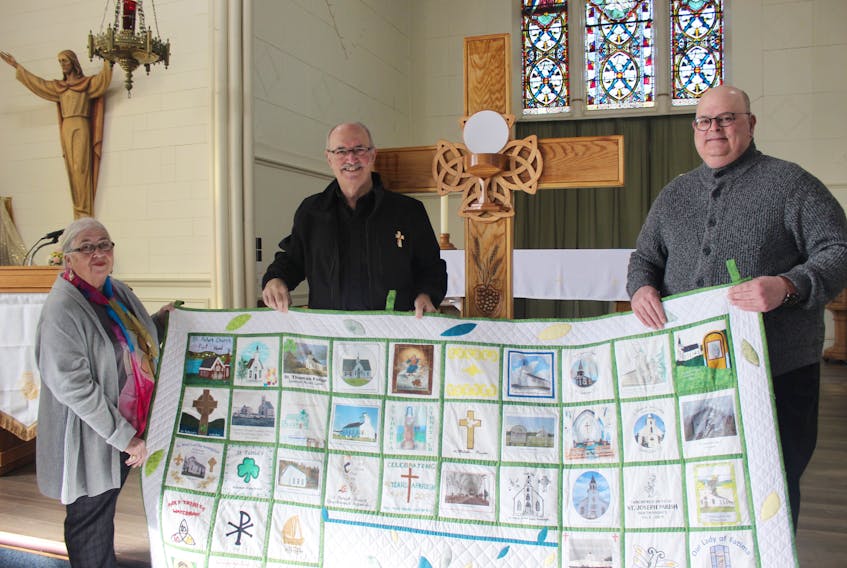 Setting up the cross and quilt for its first Pictou County stop are Fr. Barrett Clare-Johnson, right, pastor of Our Lady of Lourdes Church; Deacon Sander Burke working with St. John’s/Our Lady of Perpetual Help and Frances Campbell of the Liturgy Committee at Lourdes. The cross and quilt are touring the Diocese of Antigonish in celebration of the Year of Eucharist, and will spend a week in each of the county’s Catholic Churches between now and Feb. 21. CONTRIBUTED