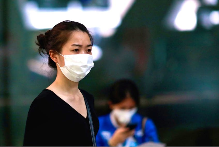 Fear of the coronavirus is prompting people around the world, such as this woman in Thailand, to wear face masks. Sales of face masks are brisk in St. John’s. REUTERS