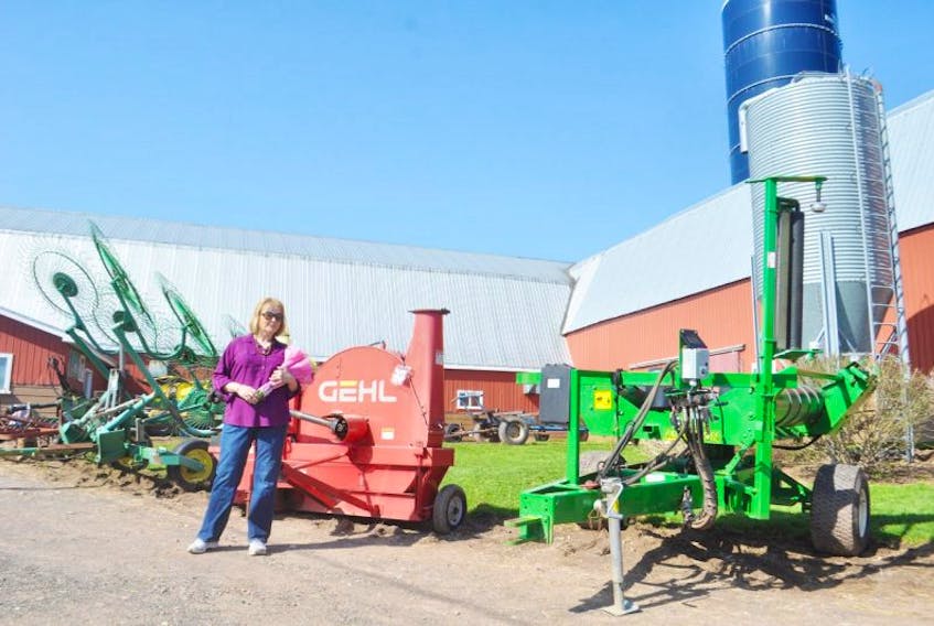 <p class="copyright">Bonnie Sutherland stands May 9 with a bouquet in her arms given to her by the auctioneer who was going to be auctioning off her farm equipment. Behind her are the implements of her farm that were sold Friday.</p>