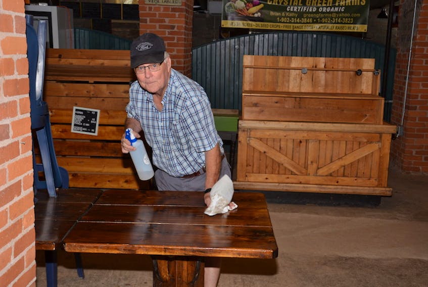 Summerside Farmers’ Market manager Don MacDonald sanitizes a table in preparation for the market moving back indoors at the Holman Building on Saturday, Sept. 19.