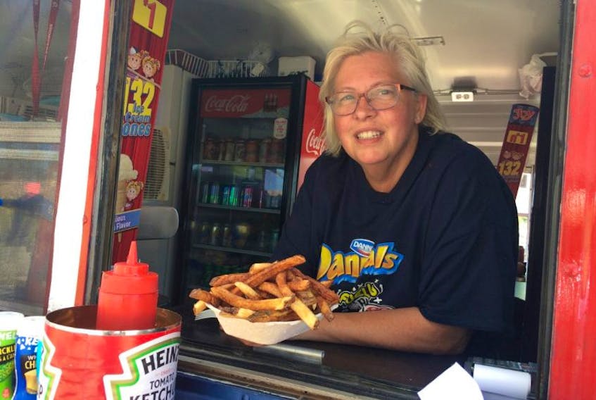 Sandy Mosel, co-owner of Red’s in Toney River, serves up an order of hand cut fries from the bus’s window. Red’s started serving in June and has regular customers in the area coming back for more hot meals and ice cream. 