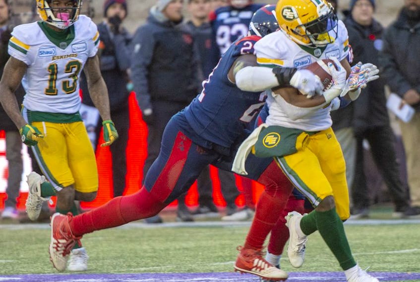 CP-Web.  Edmonton Eskimos running back Shaquille Cooper (25) is tackled by Montreal Alouettes linebacker Chris Ackie (21) as Edmonton Eskimos wide receiver Ricky Collins Jr. (13) looks on during second half CFL East Semifinal football action Sunday, November 10, 2019 in Montreal.