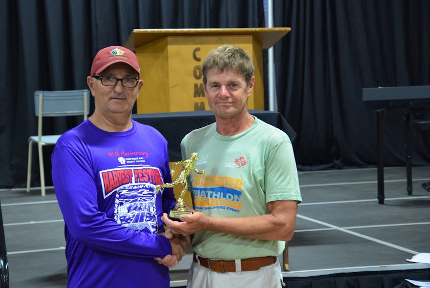 Harvest Festival 25-Kilometre Road Race director Ivan Gallant, left, presents Wayne Gairns with the award for most dedicated runner following Saturday morning’s race. Gairns has battled cancer three times.