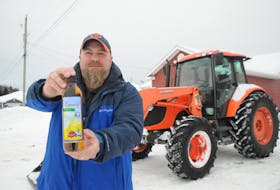 Tom Hickey displays a bottle of cold-pressed virgin canola oil produced by Sweet Berry Farms of Black Duck Siding. He jointly owns the farm with his brother Kyle Hickey. FRANK GALE/THE WESTERN STAR