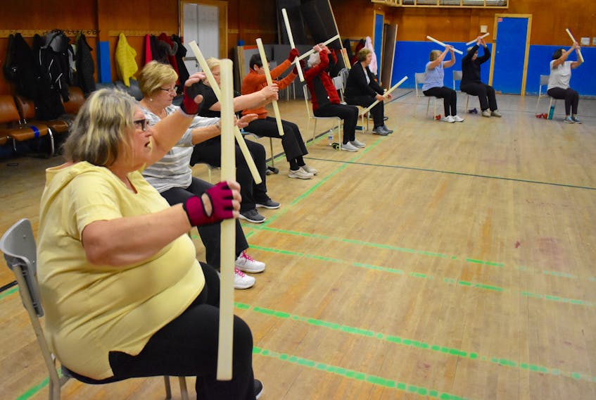 Pauline McIsaac, left foreground, moves to the rhythm of a lively soundtrack during a senior women’s workout at Knox Hall in Glace Bay on last week. About 30 participants turned up for the session that is held every weekday at 10 a.m. at the downtown Glace Bay venue. Here the women are utilizing hollow plastic tubes as a way of limbering up during the chair portion of the exercise. DAVID JALA/CAPE BRETON POST