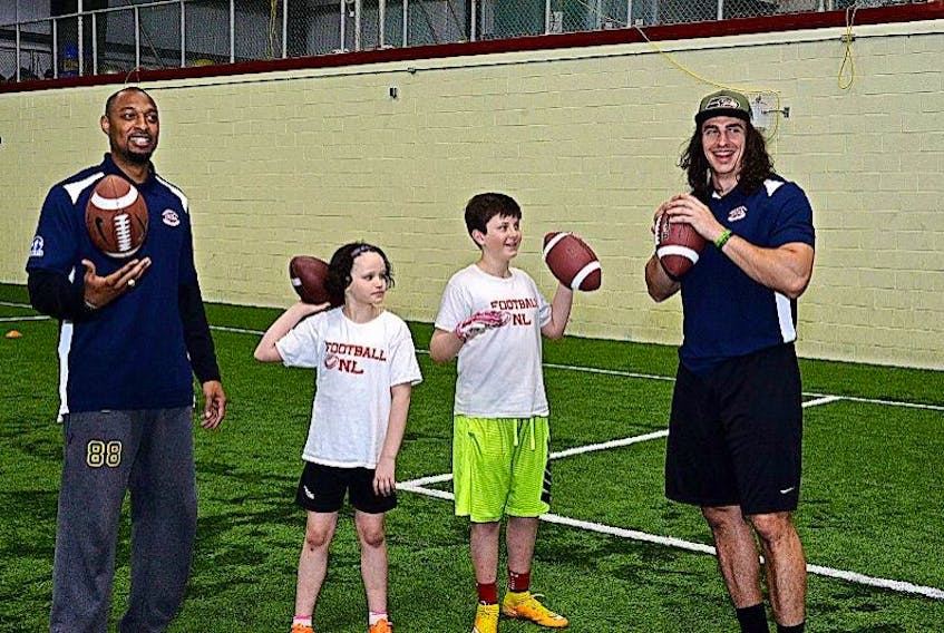 Pro football players Akeem Foster (left) of the Canadian Football League's Edmonton Eskimos and Luke Willson (right) of the National Football League’s Seattle SeaHawks were in St. John’s this weekend lending their expertise to the first-ever Football Newfoundland and Labrador annual clinic at the Techniplex in Pleasantville. Here, they are shown with Jessica MacDonald, 9, and Ben Basha, 14, in a passing drill. MacDonald was the only girl at the camp.