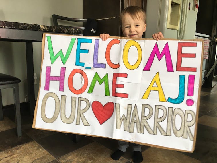 AJ with the welcome home sign his cousins Kristen and Racheal Walsh made for him. COLIN FARRELL/THE SOUTHERN GAZETTE