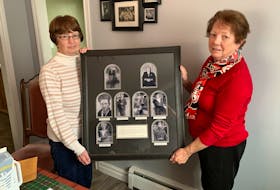 Margie Osmond (left) and her sister, Cathy Breen, both of St. John’s, hold a framed display of photos of their grandparents, along with their four uncles, who were killed during the Second World War. — ROSIE MULLALEY/The Telegram