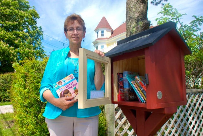 <p>Kathy Stockman with her Little Free Library at 37 Brunswick St. in Yarmouth.</p>