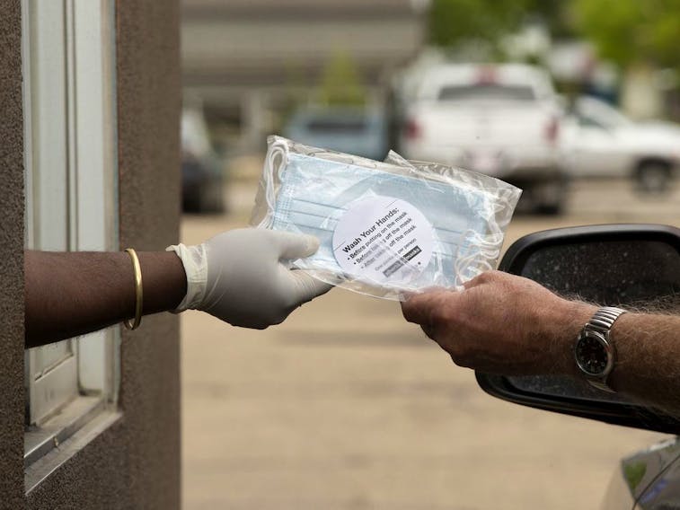 An employee at the 7455 101 Avenue A&amp;W location gives out a package of non-medical masks in the restaurant's drive-thru, in Edmonton Monday June 8, 2020. In an effort to prevent the spread of COVID-19 the Province is distributing 20 million free, non-medical face masks through A&amp;W, McDonald's, and Tim Hortons drive-thrus. 