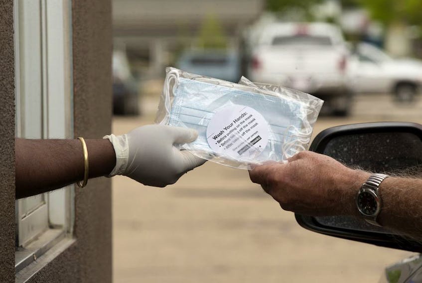 An employee at the 7455 101 Avenue A&amp;W location gives out a package of non-medical masks in the restaurant's drive-thru, in Edmonton Monday June 8, 2020. In an effort to prevent the spread of COVID-19 the Province is distributing 20 million free, non-medical face masks through A&amp;W, McDonald's, and Tim Hortons drive-thrus. 