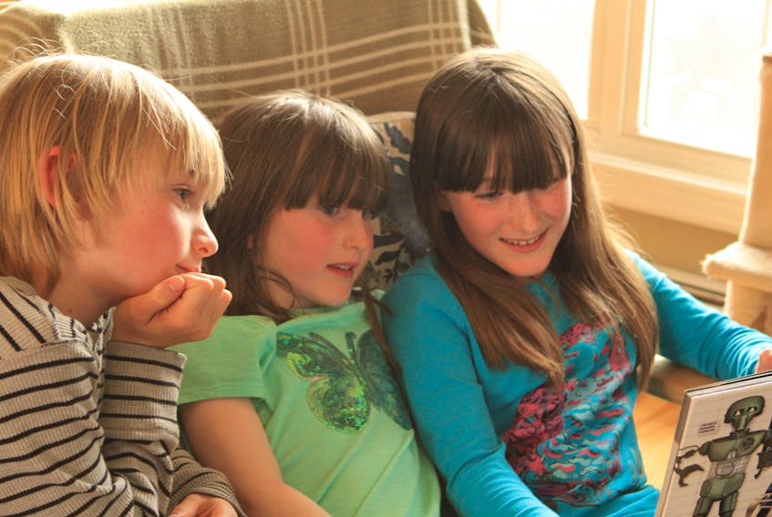 Nine-year-old Kaia Craik, right, reads to her siblings, seven-year-old Silas and six-year-old Freya. The Antigonish girl shares some of the ways her life has changed since COVID-19 began impacting the East Coast.
