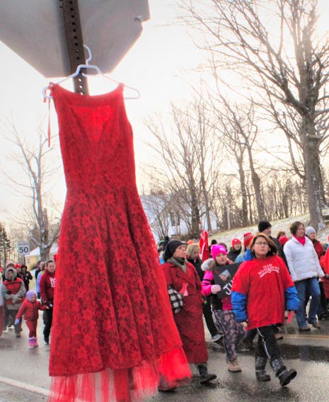 In this file photo, a red dress symbolizing missing and murdered Indigenous women was hung from a stop sign as a solemn group of about 70 people made their way toward Cassidy Bernard’s hometown of We’koma’q.