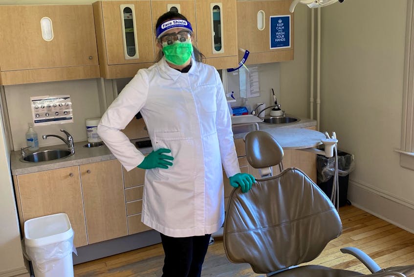 Dr. Elizabeth Jackson, a dentist at the Cornwallis Dental Centre in Kentville, N.S., shows off the new uniform for dentists. Regulations require dentists to now wear a lab jacket or gown, and either wear goggles and an N95 mask or a surgical mask with a face shield. They also now must wear scrubs and dedicated clinic shoes. They will continue to wear gloves during appointments and must always wear a mask while in the office when social distancing cannot be maintained.
