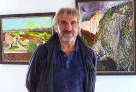 Jean Claude Roy stands between two of his new paintings at the Emma Butler Gallery in downtown St. John's. The painting on the left was painted while he strapped himself to the top of his stone farmhouse in La Clisse, France. The painting on the right was painted while sitting on the La Manche suspension bridge on the East Coast Trail. — Andrew Waterman/The Telegram