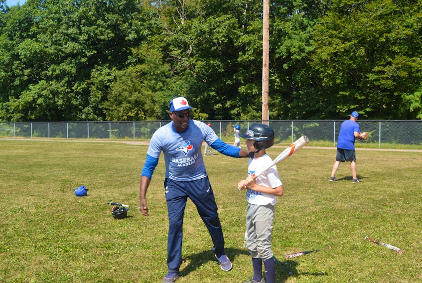 Former Toronto Blue Jays outfielder Lloyd Moseby goes over some hitting drills with one of the many participants Wednesday at the Blue Jays Baseball Academy camp at Memorial Field in Charlottetown.
