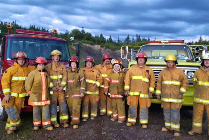 <p>Members of the Random West Volunteer Fire Department stand in front of their two fire trucks.&nbsp;</p>