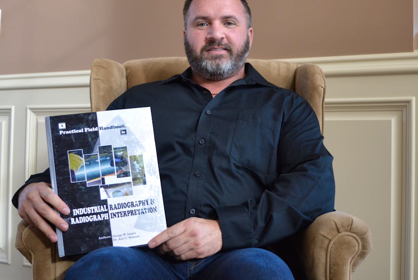 George Jaques holds a copy of his book “A Practical Field Handbook in Industrial Radiography and Radiograph Interpretation” at his home in Georges River. The book recently won the American Society for Quality’s Philipe B. Crosby Medal. CAPE BRETON POST