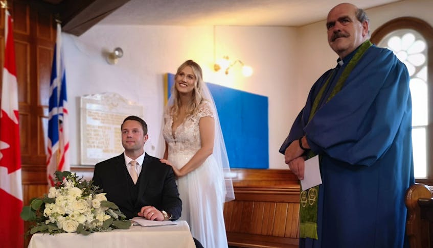 After months of delivering services to an empty church, Reverend Bill Mercer jumped at the opportunity to perform a wedding ceremony. Here, Tara and Richard Barry make it official by signing the marriage certificate. – Andrew Waterman/The Telegram