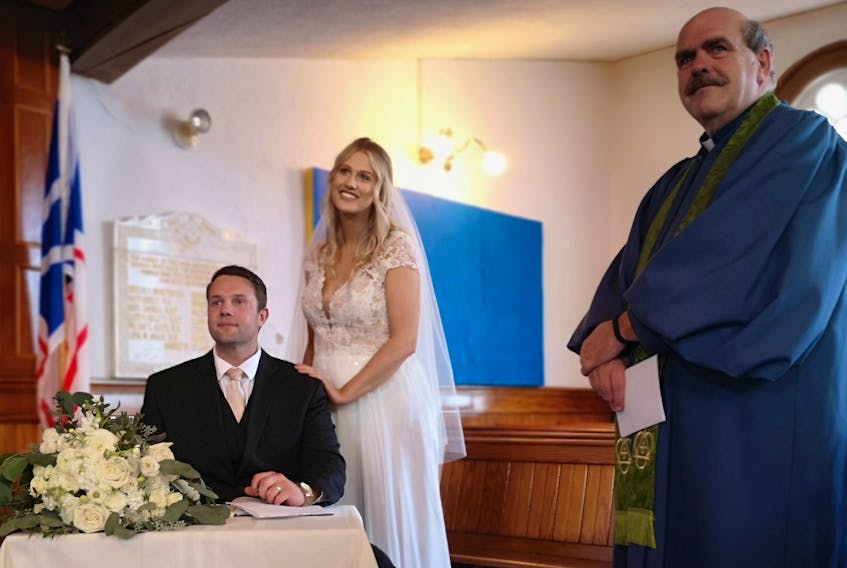 After months of delivering services to an empty church, Reverend Bill Mercer jumped at the opportunity to perform a wedding ceremony. Here, Tara and Richard Barry make it official by signing the marriage certificate. – Andrew Waterman/The Telegram