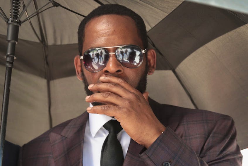 R&amp;B singer R. Kelly covers his mouth as he speaks to members of his entourage as he leaves the Leighton Criminal Courts Building following a hearing on June 26, 2019 in Chicago, Illinois. 