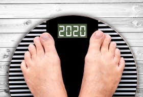 2020 feet on a weight scale on white planks, new year and holiday food nutrition and diet concept.