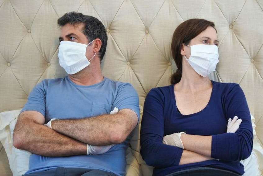 An upsets couple in isolation wear face masks and protective gloves.