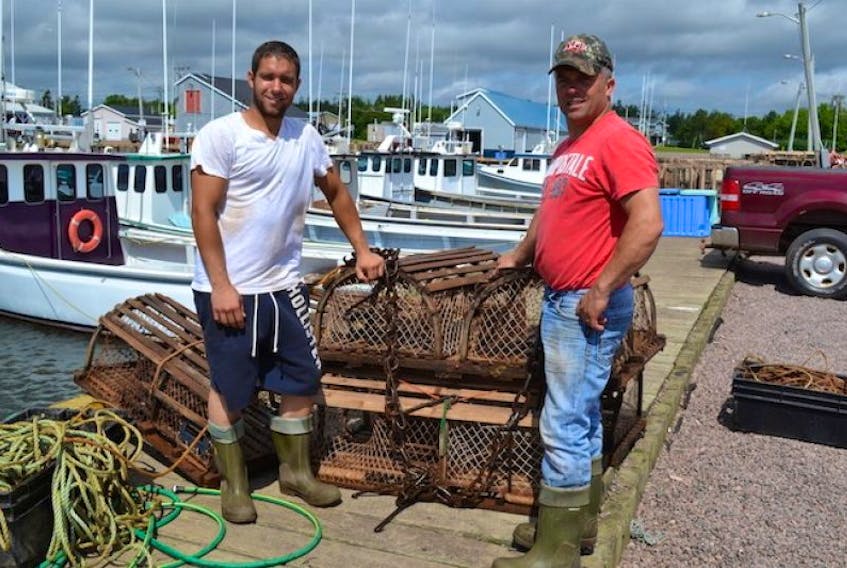 Jordan Lewis, left, and David Lewis display the ghost traps they found Friday during a sweep of north side lobster fishing grounds. Thirteen fishing boats from Sea Cow Pond to French River assisted three fisheries patrol crews in the sweep, helping to find about 30 traps. The lobster in the traps were liberated.