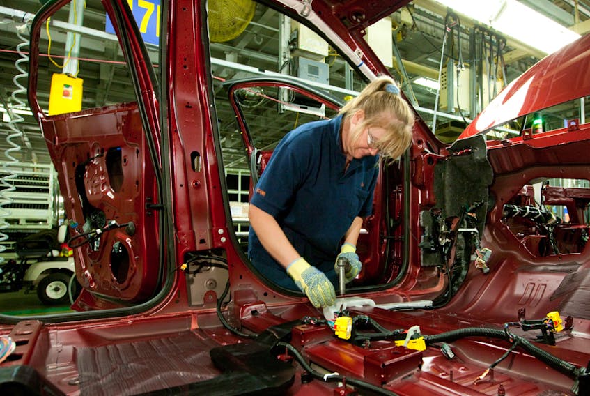 A worker installs parts into the interior of a GMC vehicle at the CAMI Automotive Inc. plant assembly line in Ingersoll, Ont.