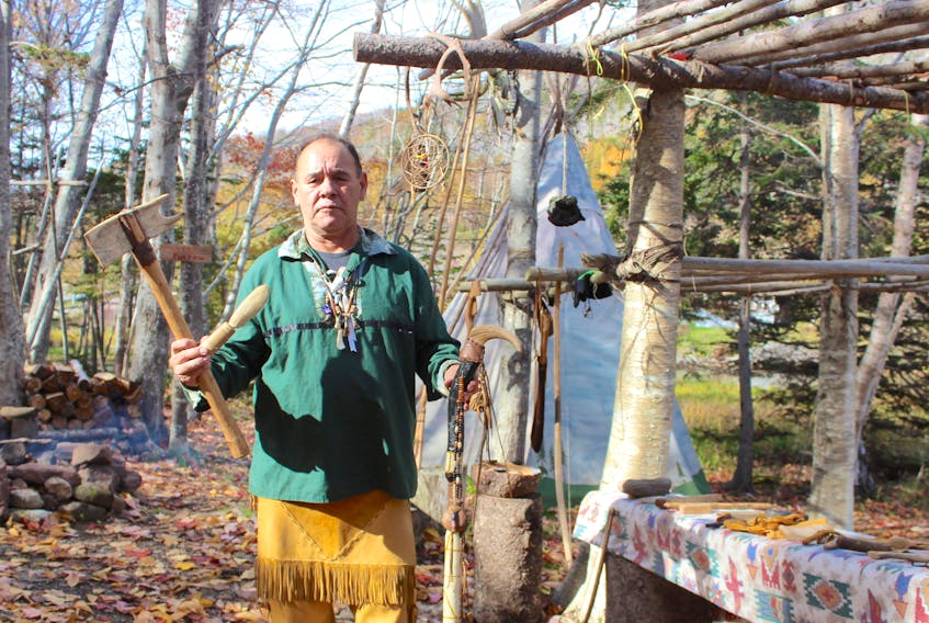 Charles Francis holds an axe and knife fashioned from moose antler, as well as an elaborately-carved walking stick that would have been a sign of wealth and status in traditional times.