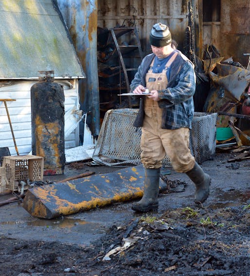 Woodland Farm owner Mike Dinn Jr. assesses the damage of a garage that was destroyed by fire Saturday afternoon on the property, located on Black Line in the Goulds.  – KEITH GOSSE/The Telegram