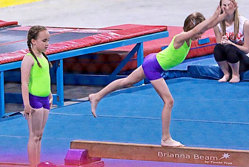With both dressed as the Incredible Hulk, gymnast Bree Anstey, left, waits her turn as teammate Alyssa Leboubon completes her routine on the balance beam.<br />Roxanne Ryland photo