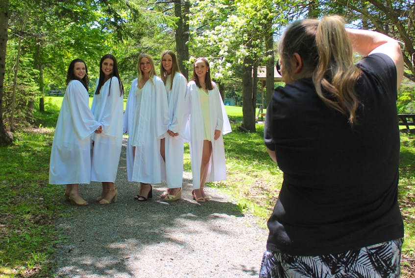 Riverview Rural High School grads Emma MacPhee, from left, Erin MacIsaac, Julia Currie, Gillian Ellerker and Julie MacLeod smile as photographer Anita Clemens takes their photos in Petersfield Provincial Park in Westmount on Tuesday. Chris Connors/Cape Breton Post