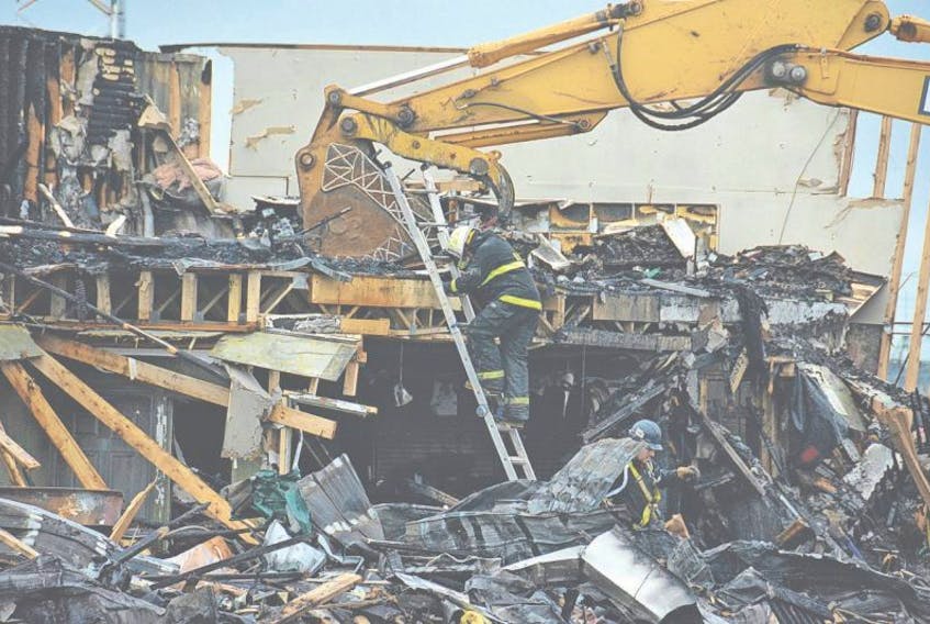 Crews search through the rubble of Green Diamond Equipment for any firearms or ammunition that could pose a danger. The John Deere dealership and outfitter burned Saturday morning.
