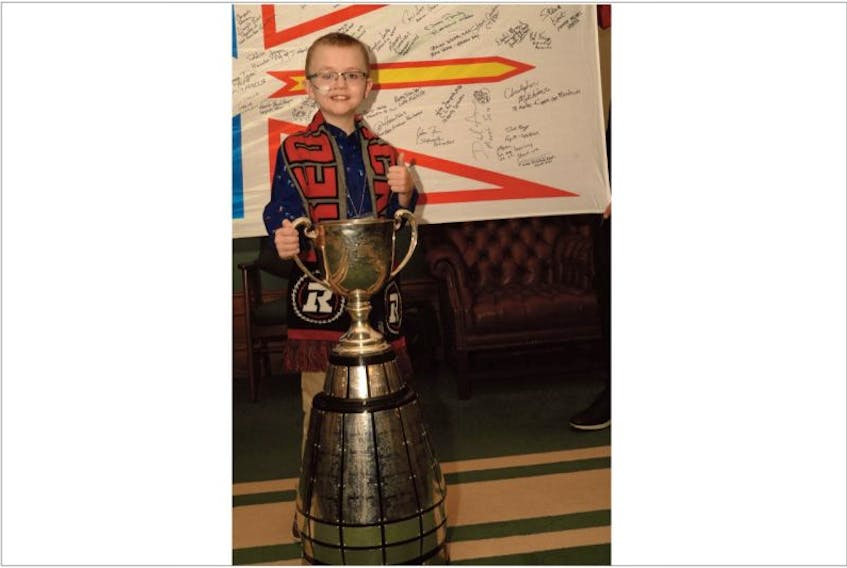 Steven Sullivan, 9, poses with the Grey Cup and a Newfoundland and Labrador flag signed by all Members of the House of Assemby Thursday at the Confederation Building in St. John's. Steven was special guest of the CFL champion Ottawa RedBlacks, who brought the cup to the provincial seat of government.
