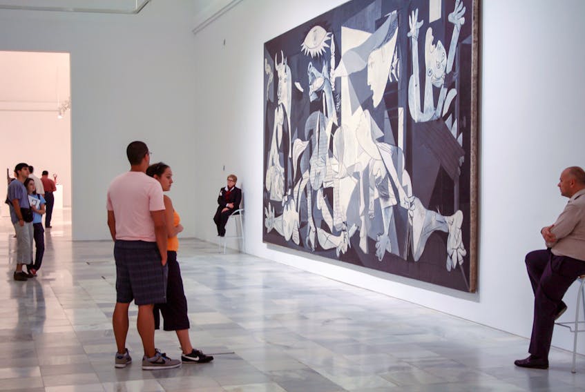 People visiting Museo Nacional Centro de Arte Reina Sofia stand before the painting by Pablo Picasso "Guernica"  commemorating the bombing during the Spanish Civil War.