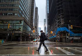 A pedestrian wearing a mask walks across a deserted Yonge Street in Toronto earlier this week. — Postmedia photo