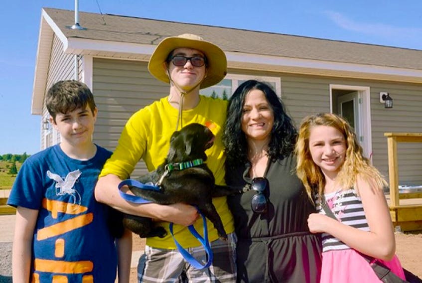 <p>Tina Ellsworth and her children, from left, Dylan, John, Chana and their pet pug Chino celebrate during the ribbon-cutting ceremony at their new Habitat for Humanity house in Harrington. While the house is basically completed, Ellsworth is planning to continue volunteering with the group to help put other P.E.I. families in the homes they deserve.</p>