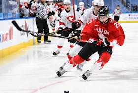 Justin Barron shields the puck from Switzerland's Lionel Marchand during a world junior championship preliminary round game in Switzerland. (IIHF)
