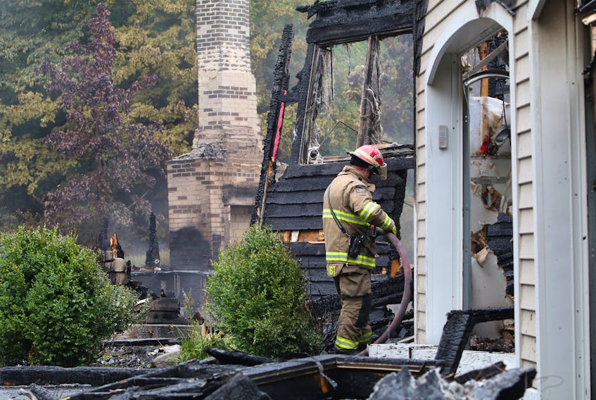 Firefighters put out hotspots at the scene of a house fire on Perfect Drive in Hammonds Plains on Wednesday.