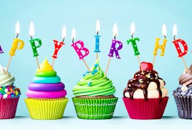Colourful cupcakes with candles spelling Happy Birthday. STOCK IMAGE
