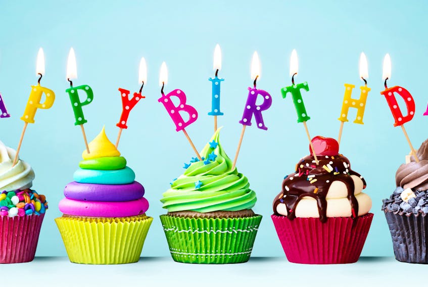 Colourful cupcakes with candles spelling Happy Birthday. STOCK IMAGE