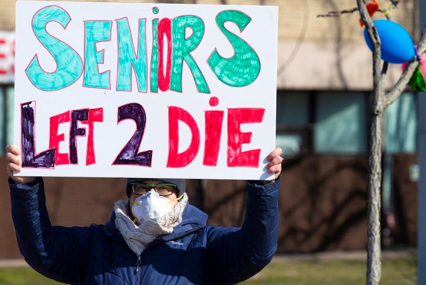  A person holds a sign outside Residence Herron, a seniors’ long-term care facility, following a number of deaths there during the COVID-19 outbreak, in the Montreal suburb of Dorval, April 11, 2020.