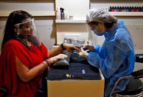  A beautician wears protective gear while tending to a customer wearing a protective face shield inside a parlour in Ahmedabad, India after authorities allowed the reopening of malls, during an extended nationwide lockdown to slow the spreading of the coronavirus disease (COVID-19), June 8, 2020.
