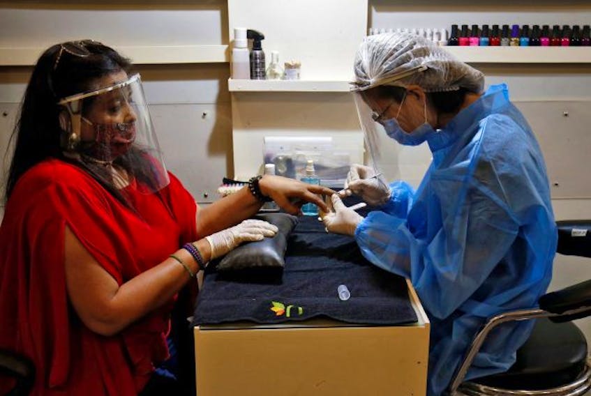  A beautician wears protective gear while tending to a customer wearing a protective face shield inside a parlour in Ahmedabad, India after authorities allowed the reopening of malls, during an extended nationwide lockdown to slow the spreading of the coronavirus disease (COVID-19), June 8, 2020.