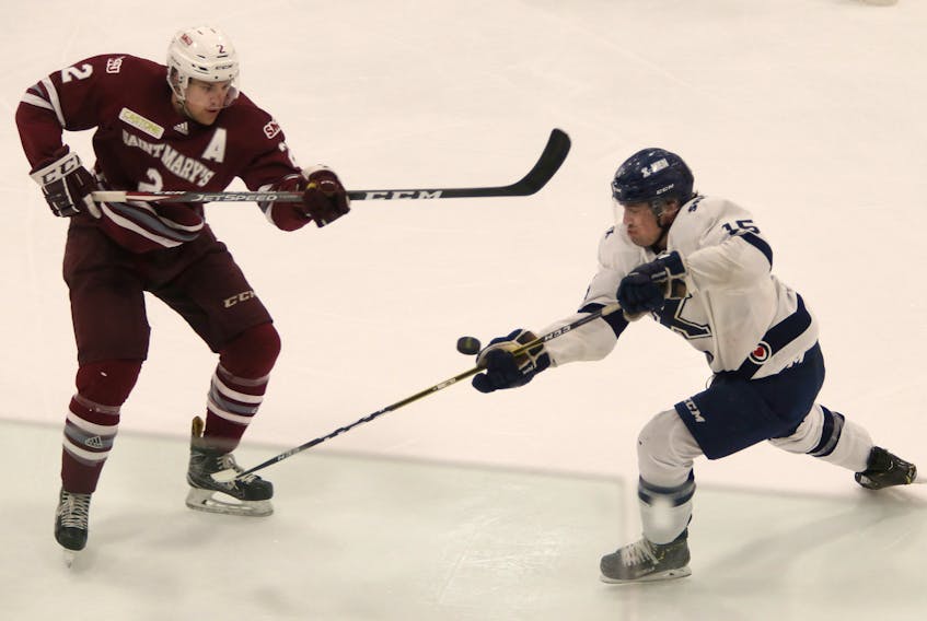 Saint Mary's Huskies defenceman Alex Peters (left) and forward Declan Smith of the St. Francis Xavier X-Men try to control a flying puck during Atlantic university hockey action last Friday at the Dauphinee Centre.   TIM KROCHAK / The Chronicle Herald 