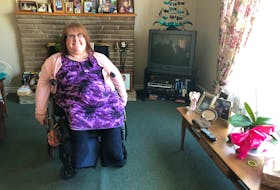 Susan Burke, 51, is surrounded by photos of her family as she sits in the living room of her Coxheath home where she grew up. Burke has spina bifida and is at high-risk for contracting COVID-19. NICOLE SULLIVAN/CAPE BRETON POST 