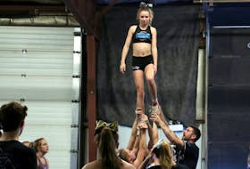 The new all-star manager and director at Integrity Cheer Empire, Chris Cunningham, works with flyer Lily Newton, of Windsor, on a move being incorporated into their routine.