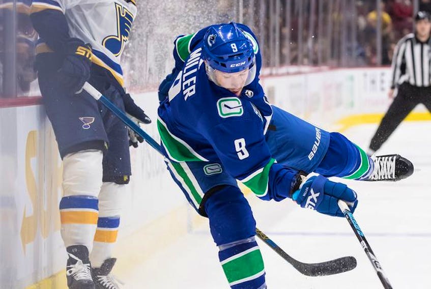  Canucks winger J.T. Miller (right) loses his footing while vying for the puck against the St. Louis Blues’ Ivan Barbashev during the first period of their NHL game in Vancouver on Monday.
